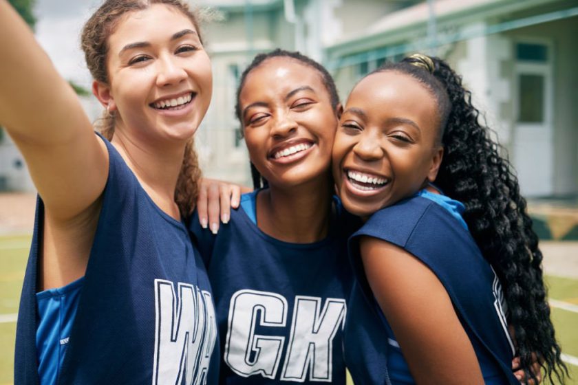 Sports, team and girl netball selfie, hug with fitness and college or school club with outdoor portrait. Exercise, competitive sport and happy people, smile in picture and player training on court.